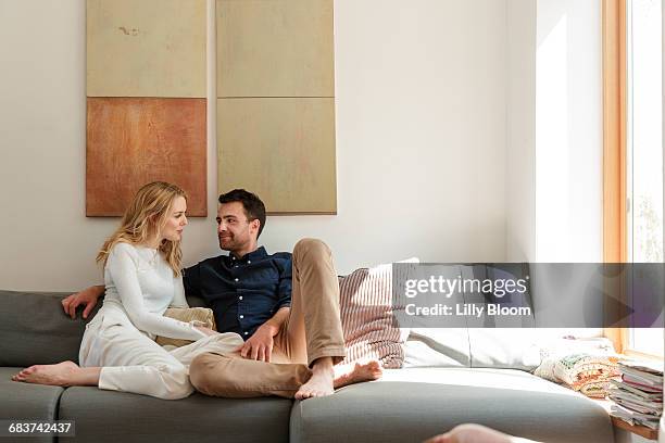 couple snuggling on sofa - sofa stock-fotos und bilder