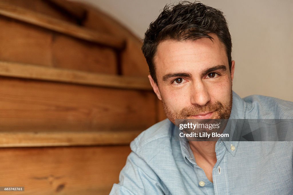 Portrait of man with stubble on stairway looking at camera