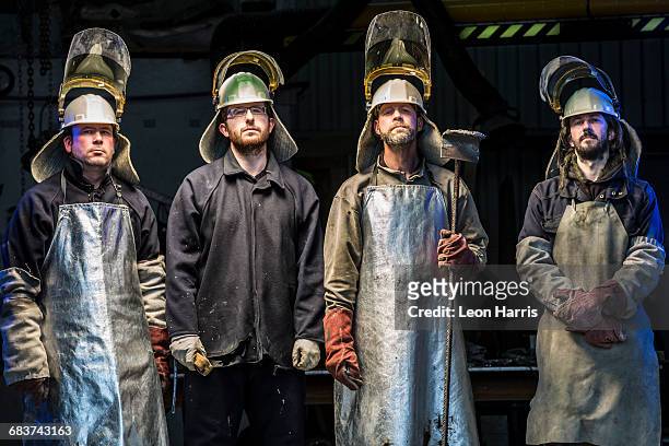 portrait of four male foundry workers wearing protective clothing in bronze foundry - welding mask stock pictures, royalty-free photos & images