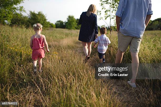 rear view of mid adult parents strolling in meadow boy and girl - oshawa 個照片及圖片檔