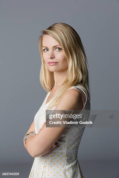 portrait of beautiful woman standing with arms crossed against gray background - sleeveless stock pictures, royalty-free photos & images