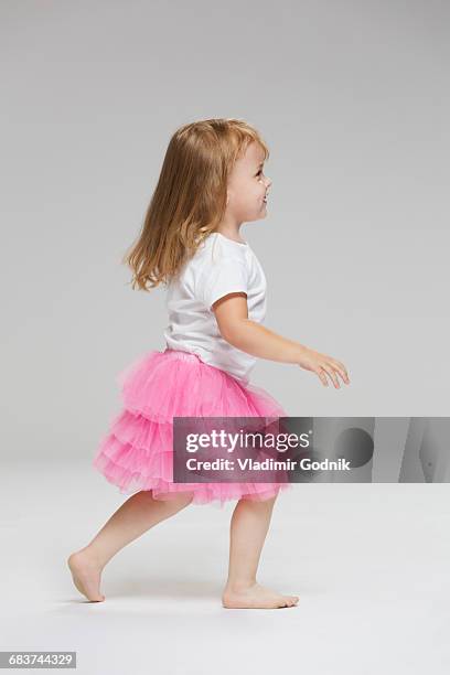 side view of girl wearing tutu playing against gray background - blonde girl smiling stock-fotos und bilder