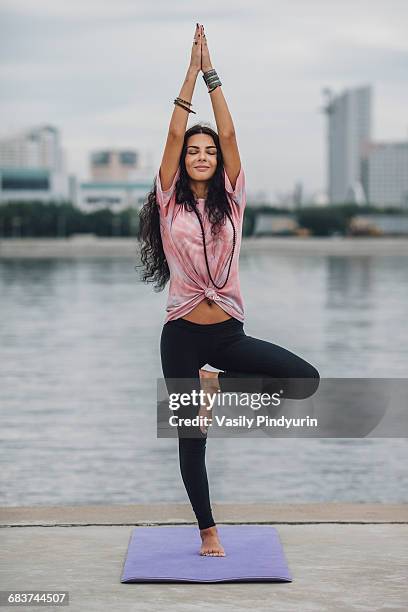 beautiful woman practicing yoga in tree pose against river - tree position stock pictures, royalty-free photos & images