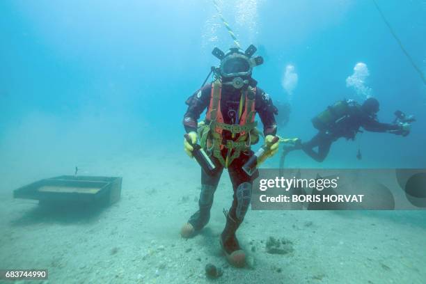 Diver takes wine bottles from an underwater trunk on May 15, 2017 in the Mediterranean sea off Saint-Mandrier, southern France. - The experiment was...