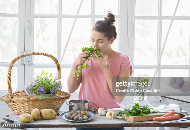 young woman smelling wild herbs at kitchen counter, vogogna,verbania, piemonte, italy - mediterrane kultur stock-fotos und bilder