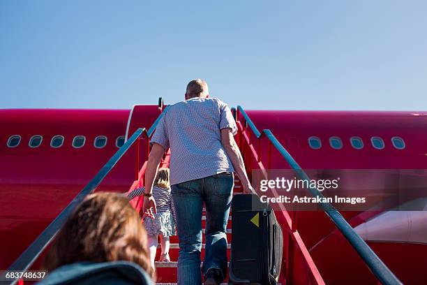 low angle view of people walking on staircase towards airplane - red plane stock pictures, royalty-free photos & images