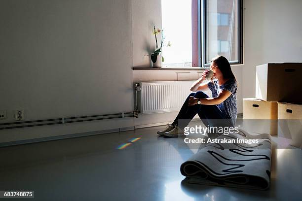 full length side view of young woman having coffee in new house - new flat stock pictures, royalty-free photos & images