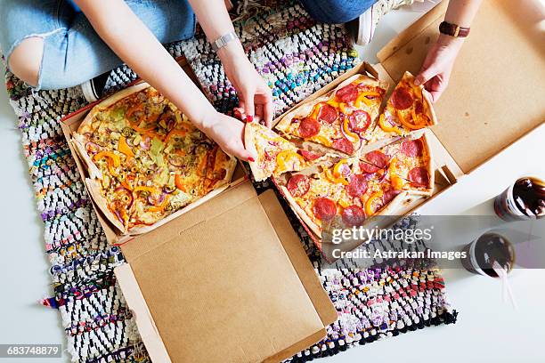 high angle view of friends eating pizza with cola in new home - pizza box stock-fotos und bilder