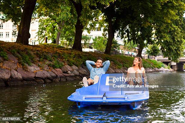 friends enjoying pedal boating on river in city - pedal boat foto e immagini stock