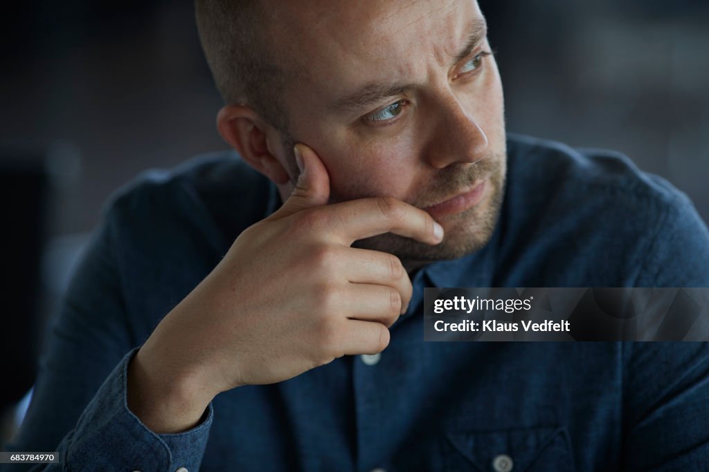 Businessman sitting in conference room, looking thoughtful
