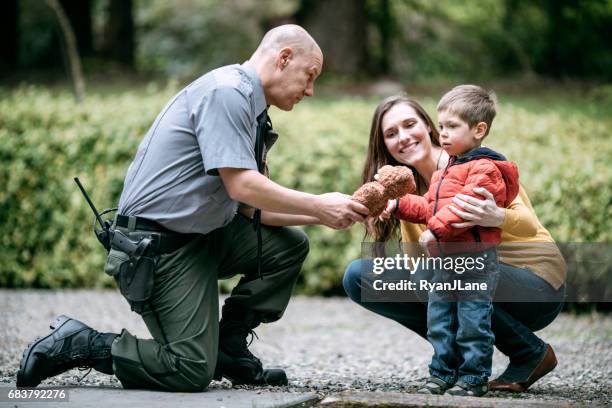 oficial de policía dando infantil peluche - police fotografías e imágenes de stock