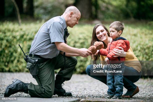 police officer giving child stuffed animal - police stock pictures, royalty-free photos & images