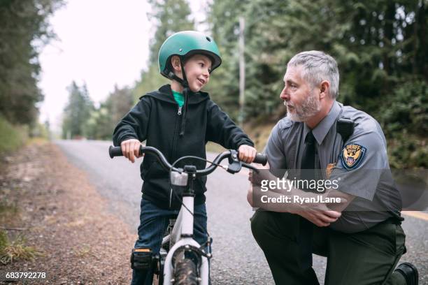 police officer talking to child on bike - police stock pictures, royalty-free photos & images