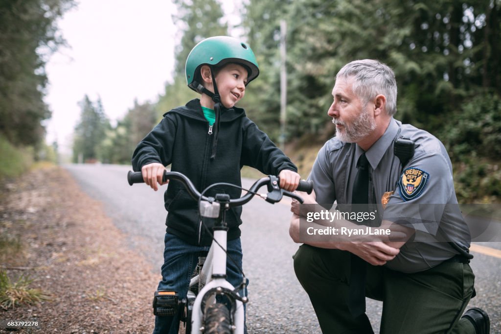 Oficial de polícia falando com criança na bicicleta