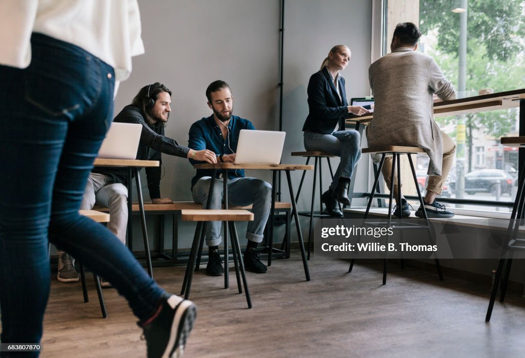 People Sitting Down And Working Together In A Busy Cafe