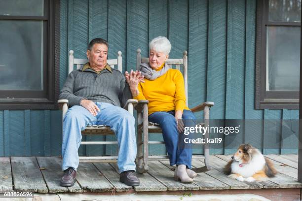 älteres paar auf veranda, hand in hand mit hund - schaukelstuhl stock-fotos und bilder