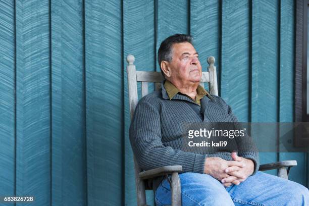 serious senior man sitting in rocking chair on porch - alpendre imagens e fotografias de stock