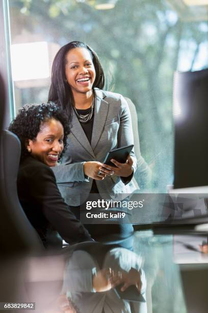 two minority businesswomen meeting in board room - boss over shoulder stock pictures, royalty-free photos & images