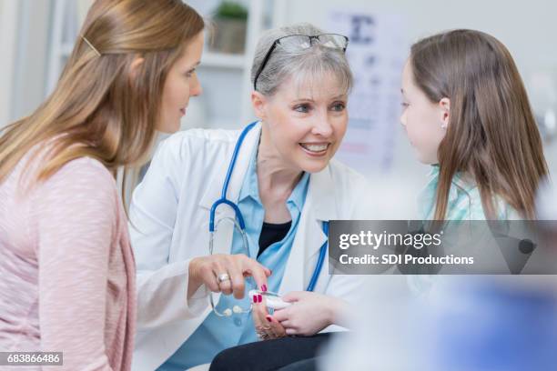 confident pediatrician teaches patient about glaucometer - glaucometer stock pictures, royalty-free photos & images