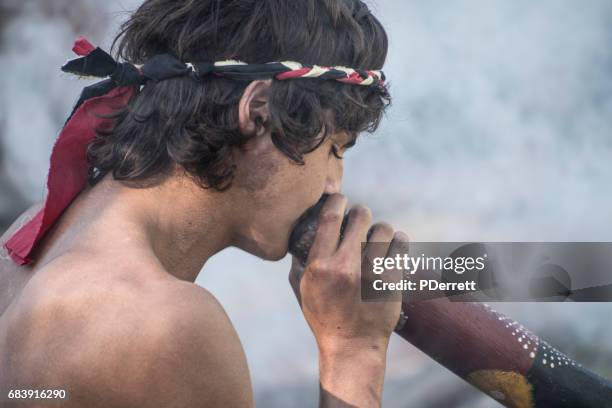 young man plays the didgeridoo at mardi grass parade. - didgeridoo stock pictures, royalty-free photos & images