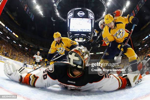 John Gibson of the Anaheim Ducks lies on the ice as he makes a save against Pontus Aberg and Mike Fisher of the Nashville Predators during the first...