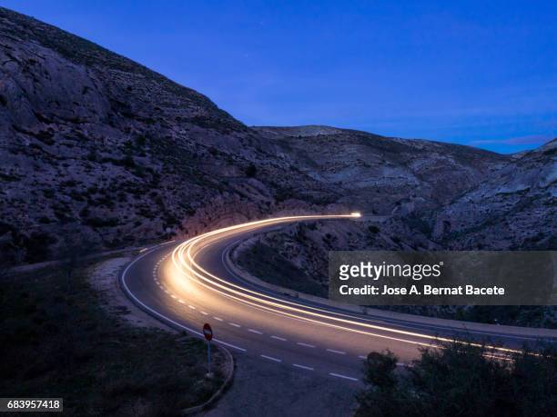 lights of vehicles circulating along a road of mountain with curves closed in the night - driving car blue stock pictures, royalty-free photos & images