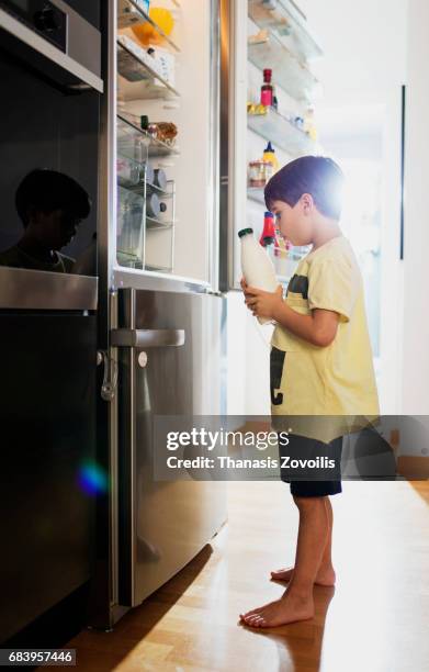 6 year old boy drinking milk near open fridge - open fridge ストックフォトと画像