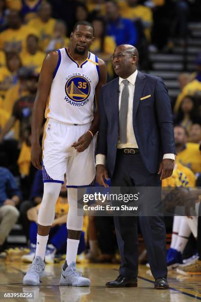 Kevin Durant of the Golden State Warriors speaks with acting head coach Mike Brown during Game Two of the NBA Western Conference Finals against the...