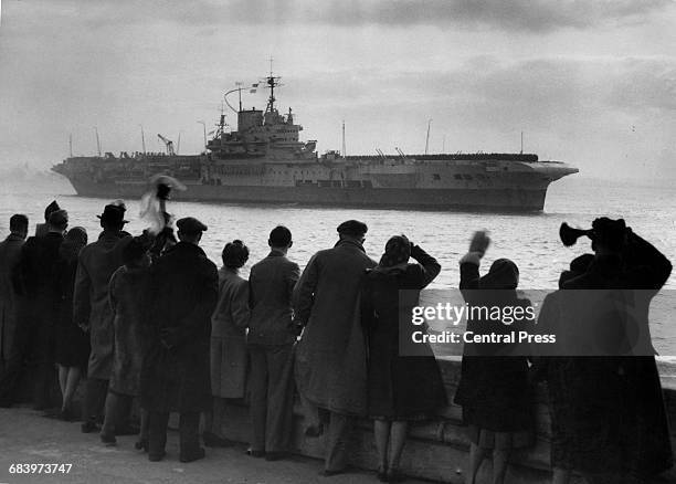 Friends and families wave from the quayside as the Royal Navy Illustrious-class aircraft carrier HMS Formidable returns to her home port of...