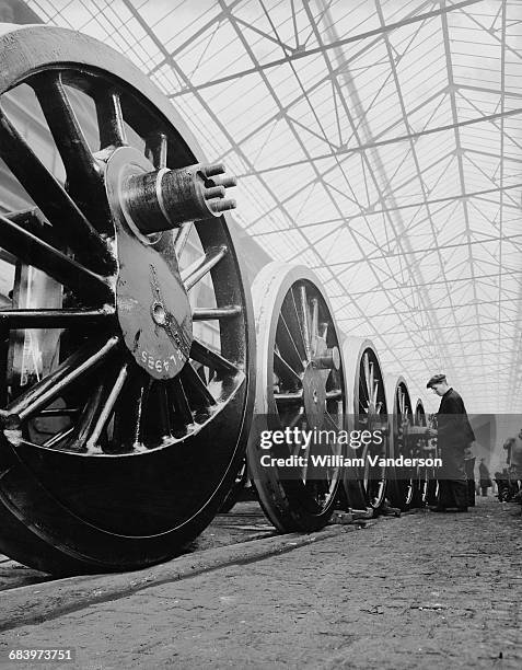 Rail workers make adjustments to the driving wheels for the London, Midland and Scottish Railway steam locomotives where they are being built at the...
