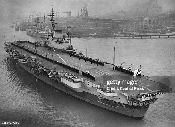 Officers and crew line the flight deck of the Royal Navy Implacable-class aircraft carrier HMS Indefatigable after returning to her home port of...