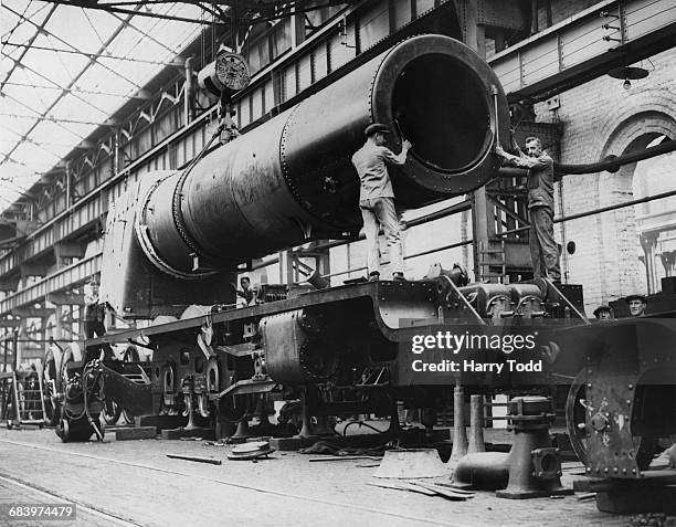 Rail workers prepare to mount the engine boiler to the main frame of the London, Midland and Scottish Railway Princess Royal Class 4-6-2 steam...