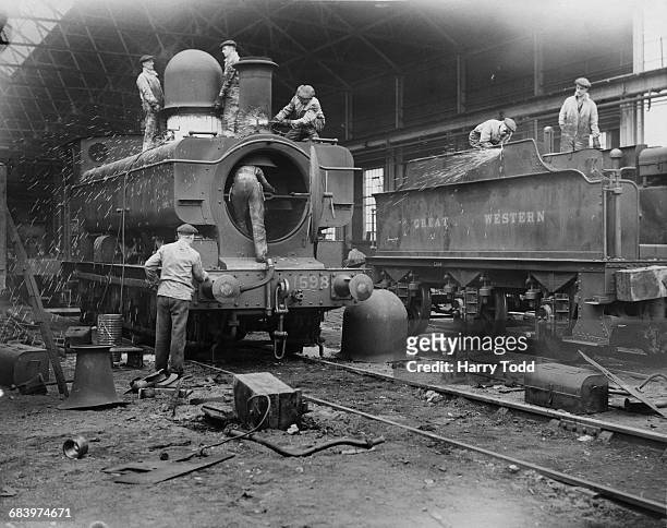 Sparks fly as rail workers using oxy-acetylene torches start cutting and breaking down older Great Western Railway GWR 1076 Class steam locomotives...