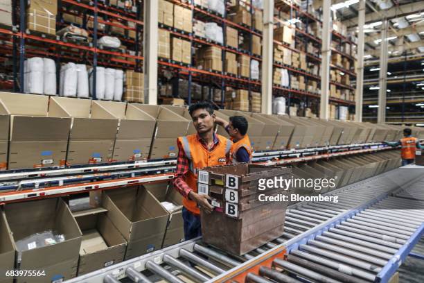 An employee lifts plastic crates at a warehouse operated by Future Supply Chain Solutions Ltd. Near the Multi-modal International Cargo Hub Airport...
