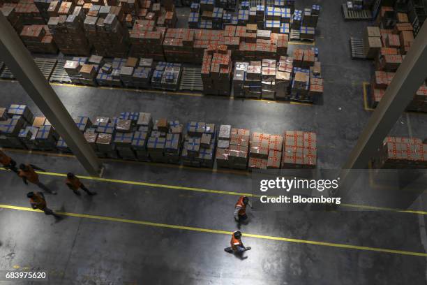 Employees walk past boxes stacked on pallets at a warehouse operated by Future Supply Chain Solutions Ltd. Near the Multi-modal Cargo International...