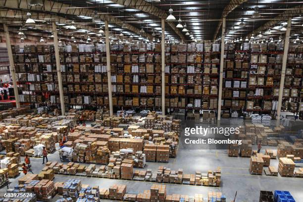 Employees walk past boxes stacked at a warehouse operated by Future Supply Chain Solutions Ltd. Near the Multi-modal Cargo International Hub Airport...