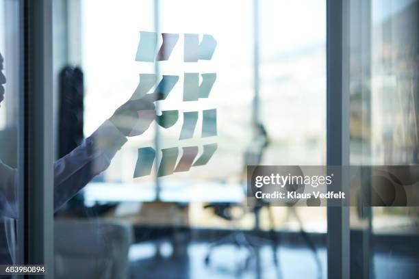 businessman sticking paper note on glass wall - flouté photos et images de collection