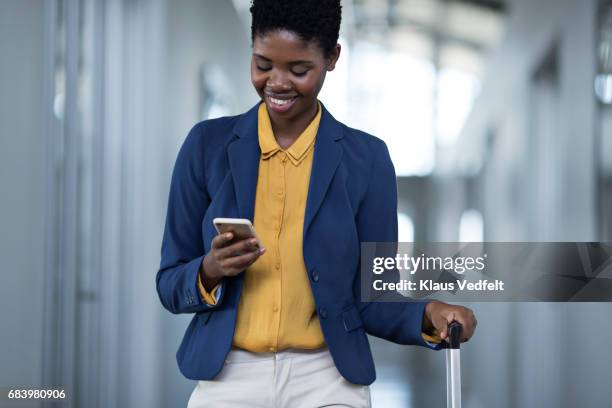 businesswoman walking down hall way, looking at smartphone - receiving text stock pictures, royalty-free photos & images