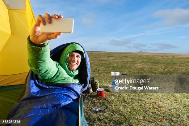 man taking self portrait with camera smartphone. - sleeping bag stock pictures, royalty-free photos & images