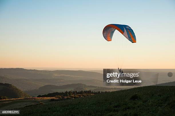 paraglider above wasserkuppe mountain at sunset - paracaídas fotografías e imágenes de stock