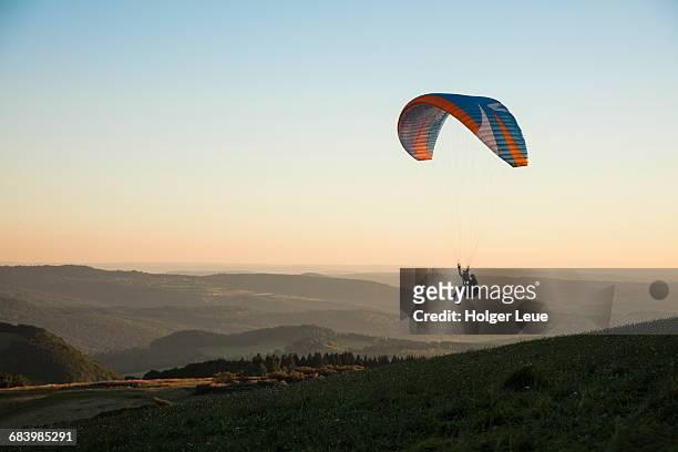 paraglider above wasserkuppe mountain at sunset - paracadutista foto e immagini stock