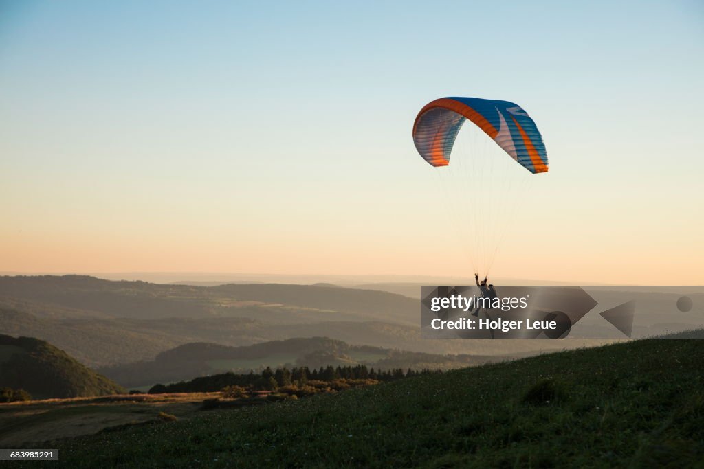 Paraglider above Wasserkuppe mountain at sunset