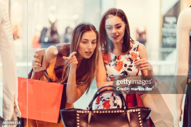 jonge vrouwen in het winkelcentrum - window shoppen stockfoto's en -beelden