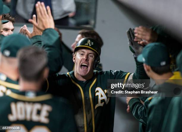 Mark Canha of the Oakland Athletics celebrates in the dugout after hitting a three-run home run off of relief pitcher Marc Rzepczynski of the Seattle...