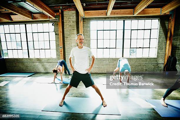 mature male yoga student laughing during class - senior yoga lady stock pictures, royalty-free photos & images