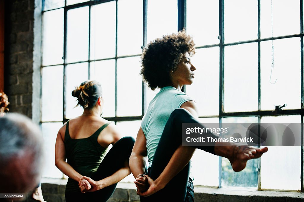 Yoga students standing in bird of paradise pose