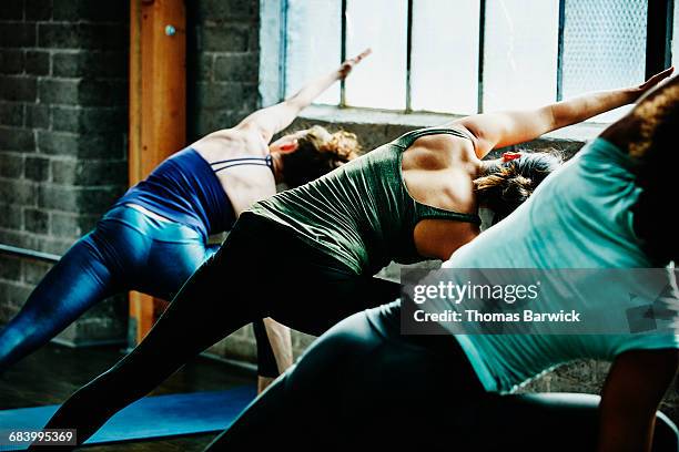 yoga students in extended side angle pose - yoga group bildbanksfoton och bilder