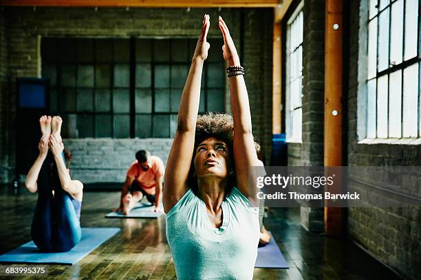 woman warming up for yoga class in studio - toples stockfoto's en -beelden