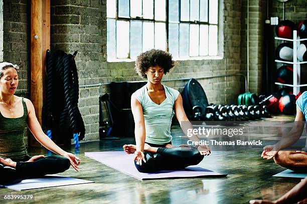 woman in lotus pose at the end of yoga class - learning agility stock pictures, royalty-free photos & images