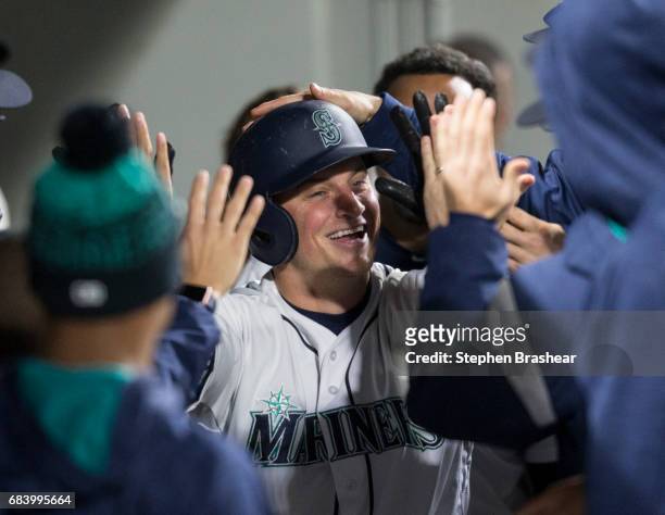 Kyle Seager of the Seattle Mariners is congratulated by teammates in the dugout after hitting a solo home run off of relief pitcher Ryan Madson of...